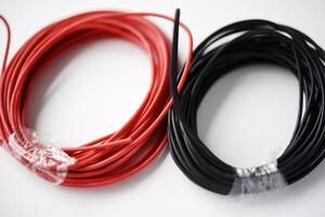 draden voor elektronica Aan een wit achtergrond. twee wikkelen van rood en zwart draden. foto