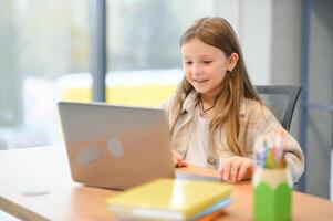 wauw, online school. gelukkig schoolmeisje Bij laptop aan het leren. online les en leerzaam aanbod poseren Bij huis foto