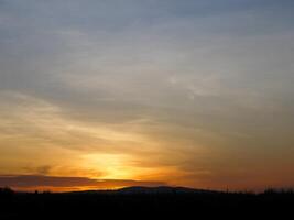 spectaculair zonsondergang over, oranje zon stijgende lijn omhoog over- de horizon foto