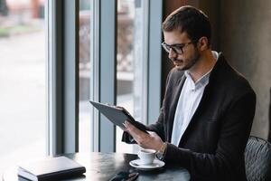 een Mens zittend in een cafe met tablet. gewoontjes Mens gebruik makend van tablet computer zittend in cafe surfing internet foto