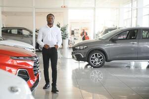 jong Afrikaanse Amerikaans auto handel opdrachtgever staand in voertuig toonzaal foto
