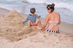 moeder en zoon spelen Aan de strand Bij de zonsondergang tijd. concept van vriendelijk familie foto