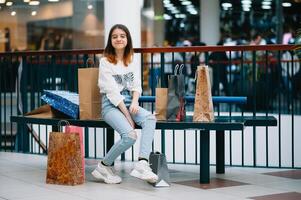 kleinhandel, gebaar en uitverkoop concept - glimlachen tiener- meisje met veel boodschappen doen Tassen Bij winkelcentrum foto
