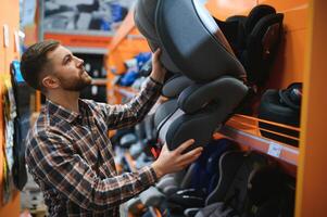 jong mannetje met auto stoel voor kinderen in de kinderen op te slaan foto