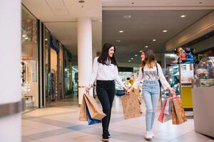 mooi jong mam en tiener- dochter zijn Holding boodschappen doen Tassen en glimlachen terwijl aan het doen boodschappen doen in winkelcentrum. familie boodschappen doen foto