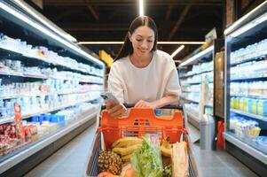 vrouw klant toepassingen mobiel telefoon in supermarkt foto