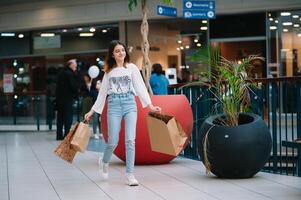 boodschappen doen tijd, tiener- meisje met boodschappen doen Tassen Bij boodschappen doen winkelcentrum. boodschappen doen concept. foto