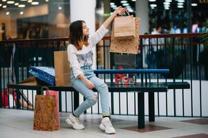 kleinhandel, gebaar en uitverkoop concept - glimlachen tiener- meisje met veel boodschappen doen Tassen Bij winkelcentrum foto