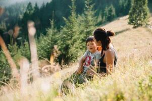 jong mam met baby jongen reizend. moeder Aan wandelen avontuur met kind, familie reis in bergen. nationaal park. wandeltocht met kinderen. actief zomer vakantie. vissenoog lens. foto