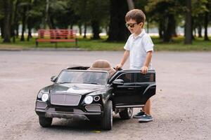 schattig jongen in rijden een zwart elektrisch auto in de park. grappig jongen ritten Aan een speelgoed- elektrisch auto. kopiëren ruimte. foto