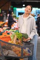 jong vrouw buying groenten Bij kruidenier markt foto