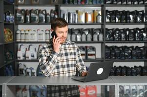 een verkoper in een auto onderdelen op te slaan is pratend naar een klant Aan de telefoon foto