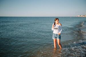 mooi meisje met mooi poten wandelen langs de kust in de zomer heet dag in de buurt de zee. foto