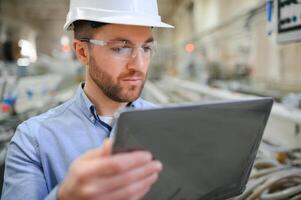 ingenieur in harde hoed is gebruik makend van een laptop in een zwaar industrie fabriek foto
