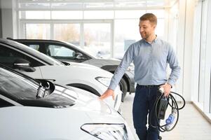 jong Mens buying eerste elektrisch auto in de toonzaal. eco auto uitverkoop concept foto