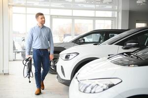 een gelukkig Mens kiest een nieuw elektrisch auto Bij een auto dealerschap. de concept van buying een ecologisch auto foto