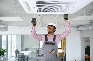 gelukkig jong Afrikaanse mannetje technicus repareren lucht conditioner foto