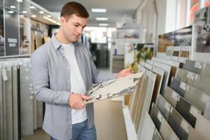 Mens kiest muur tegels voor de badkamer in de supermarkt gebouw materialen foto