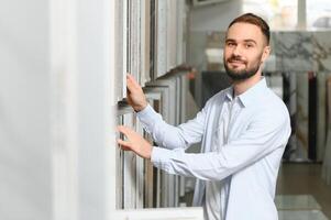 Mens kiezen keramisch tegels en gereedschap voor zijn huis badkamer foto