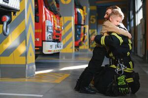 een brandweerman nemen een weinig kind jongen naar opslaan hem. brand motor auto Aan achtergrond foto