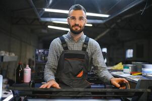 afdrukken arbeider proberen naar fix de probleem Aan computer naar bord machine in het drukken winkel foto