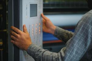 het drukken huis interieur met modern offset afdrukken machine en operator in werken uniform controle kwaliteit en controlerend werkwijze van afdrukken foto