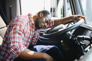 moe van werk. zittend in de cabine. jong Afrikaanse Amerikaans vrachtauto bestuurder is met zijn voertuig Bij dag. foto