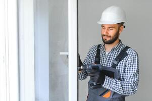 werkman in overall installeren of aanpassen plastic ramen in de leven kamer Bij huis foto