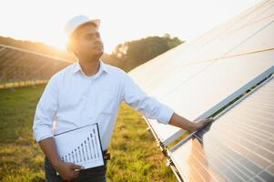 een Indisch mannetje ingenieur werken Aan een veld- van zonne- panelen. de concept van hernieuwbaar energie foto