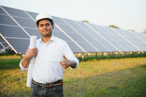 een Indisch mannetje ingenieur werken Aan een veld- van zonne- panelen. de concept van hernieuwbaar energie foto