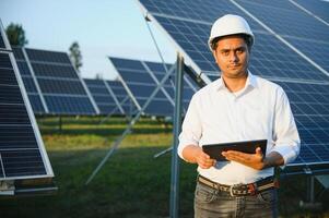 een Indisch mannetje ingenieur werken Aan een veld- van zonne- panelen. de concept van hernieuwbaar energie foto