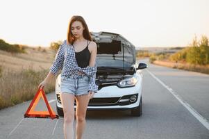 mooi sexy vrouw Holding een noodgeval hou op teken in de buurt een gebroken auto. foto