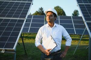 een Indisch mannetje ingenieur werken Aan een veld- van zonne- panelen. de concept van hernieuwbaar energie foto