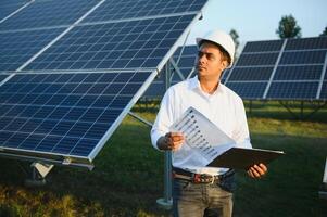 portret van een jong Indisch mannetje ingenieur of architect Bij een zonne- paneel boerderij. de concept van schoon energie foto