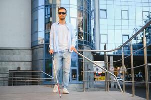 jong knap verblind Mens wandelen met stok in stad- foto