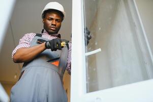 jong Afrikaanse klusjesman in uniform vaststelling glas venster met schroevedraaier foto