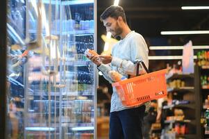 portret van gelukkig Indisch Mens staand in voorkant van de Product teller in een kruidenier op te slaan. Mens buying kruidenier voor huis in supermarkt. foto