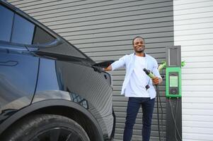 Mens opladen zijn elektrisch auto Bij in rekening brengen station foto