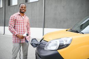 Afrikaanse Amerikaans Mens opladen zijn elektrisch auto. foto