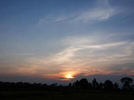 spectaculair zonsondergang over, oranje zon stijgende lijn omhoog over- de horizon foto