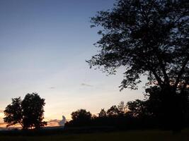 spectaculair zonsondergang over, oranje zon stijgende lijn omhoog over- de horizon foto