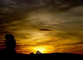 spectaculair zonsondergang over, oranje zon stijgende lijn omhoog over- de horizon foto