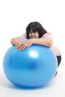 dik vrouw moe van oefening ze was leunend Aan een blauw yoga bal. wit achtergrond. gewicht verlies oefening concept. Gezondheid zorg foto