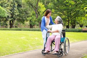 de dochter nam haar ouderen moeder in een rolstoel naar krijgen vers lucht Bij de park in de ochtend. familie concept. Gezondheid zorg voor de ouderen in pensioen leeftijd. verpleging zorg voor de ouderen. foto