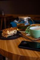 een kop van koffie en een kop van groen thee en taart Aan een houten tafel in een cafe. foto