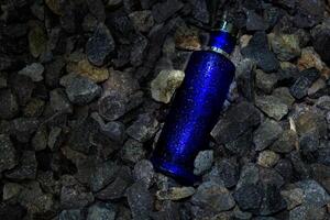 parfum donker blauw transparant fles in grind of koraal achtergrond foto