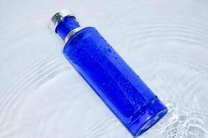 parfum donker blauw transparant fles in water achtergrond foto