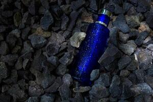 parfum donker blauw transparant fles in grind of koraal achtergrond foto