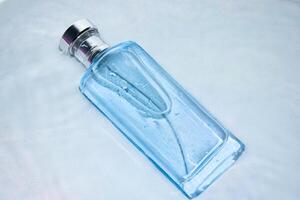 blauw fles parfum in water plons achtergrond met top hoek visie. foto