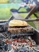 buitenshuis barbecue. vlees en pita brood Aan een rooster over- heet kolen foto